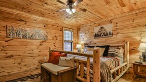 A wooden cabin bedroom with a bed, a small desk, and a ceiling fan. - 4.3 miles to BR center, Private, Family Fun, Hot Tub, Serene  (Blue Ridge)