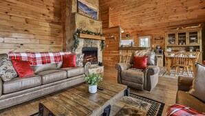 A cozy log cabin interior with a fireplace, leather sofas, and a dining area. - 4.3 miles to BR center, Private, Family Fun, Hot Tub, Serene  (Blue Ridge)