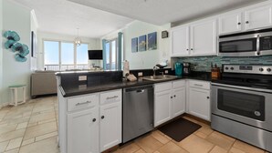 A modern kitchen with white cabinets, stainless steel appliances, and a tiled backsplash.
