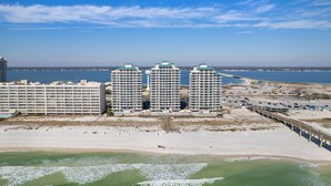 A beachfront hotel with multiple high-rise buildings, a sandy beach, and a pier extending into the ocean.