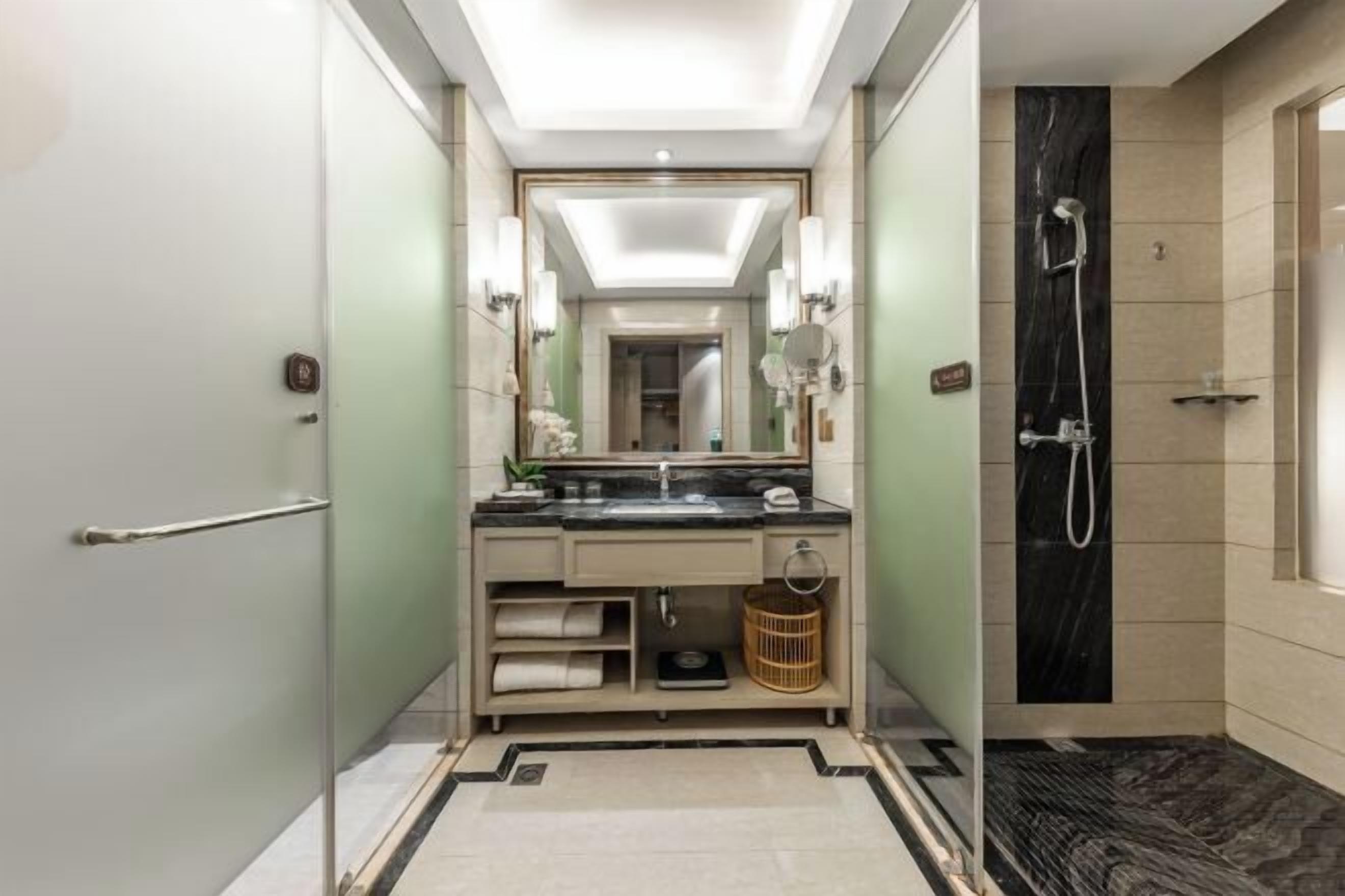 A modern bathroom with a large mirror, a sink, and a shower.
