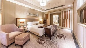A hotel room with a bed, a sofa, a desk, a nightstand, and a large mirror. - Xili International Hotel (Hong'an)