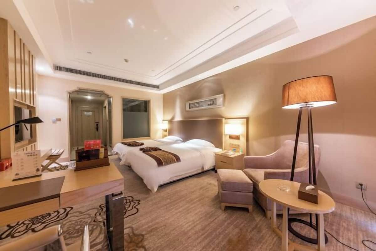Ett hotellrum med en säng, ett nattduksbord, en lampa och ett skrivbord med en stol.