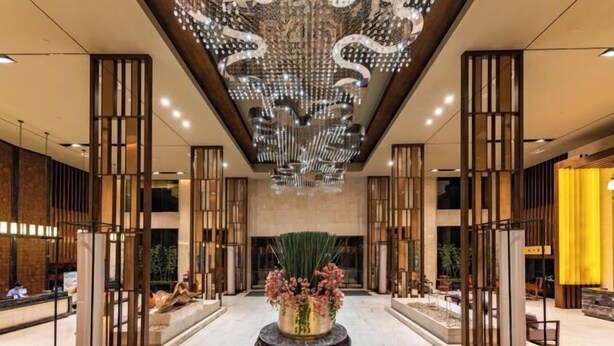 A spacious lobby with a central floral arrangement, tall decorative columns, and a modern chandelier. - Xili International Hotel (Hong'an)