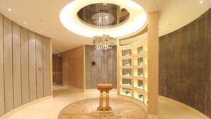 A lobby with a circular marble floor, a central column, and a chandelier. - Xili International Hotel (Hong'an)