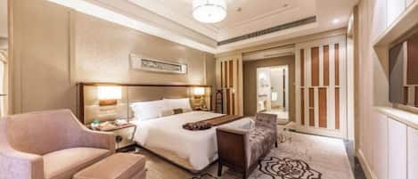 A hotel room with a large bed, a sofa, a desk, and a decorative rug.