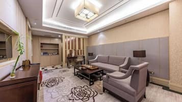 A modern living room with a sofa, armchairs, a coffee table, and a TV.
