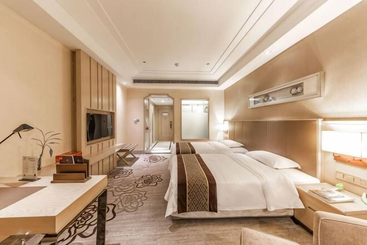 Ett hotellrum med en stor säng, sängbord, en tv, ett skrivbord och ett badrum.