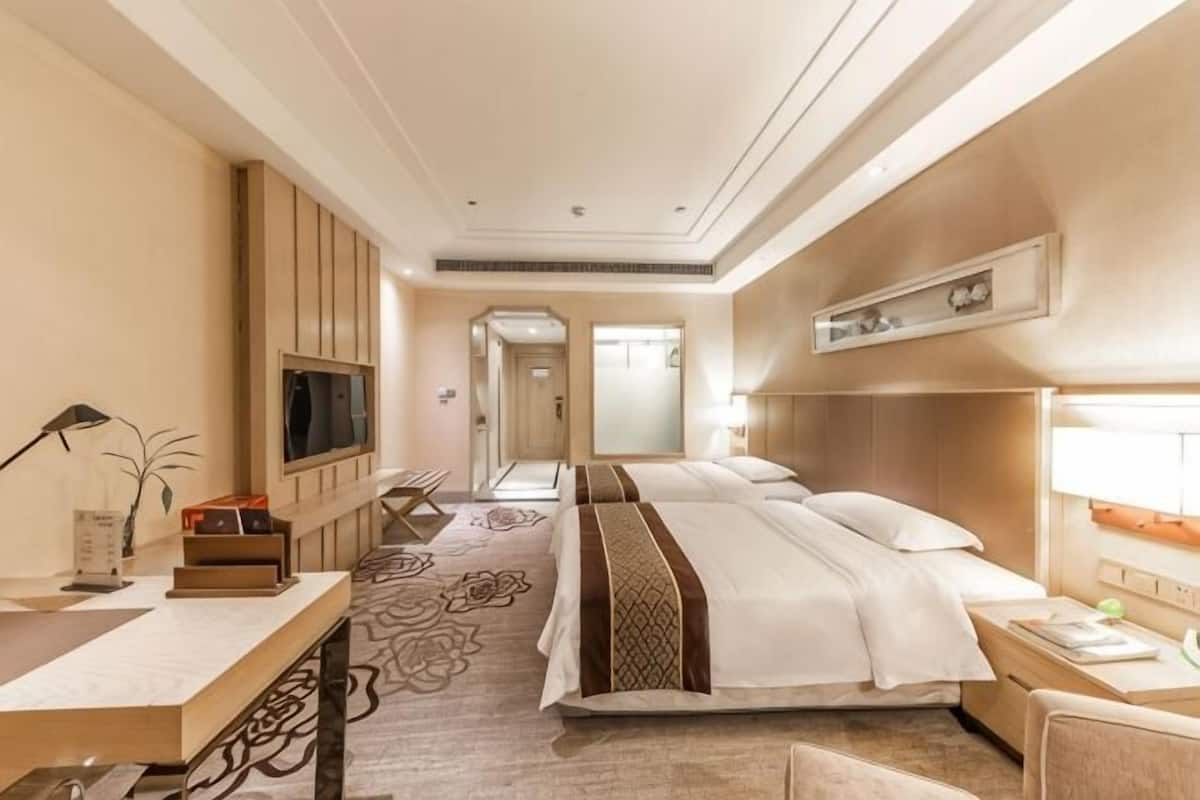 A hotel room with a large bed, bedside tables, a TV, a desk, and a bathroom.