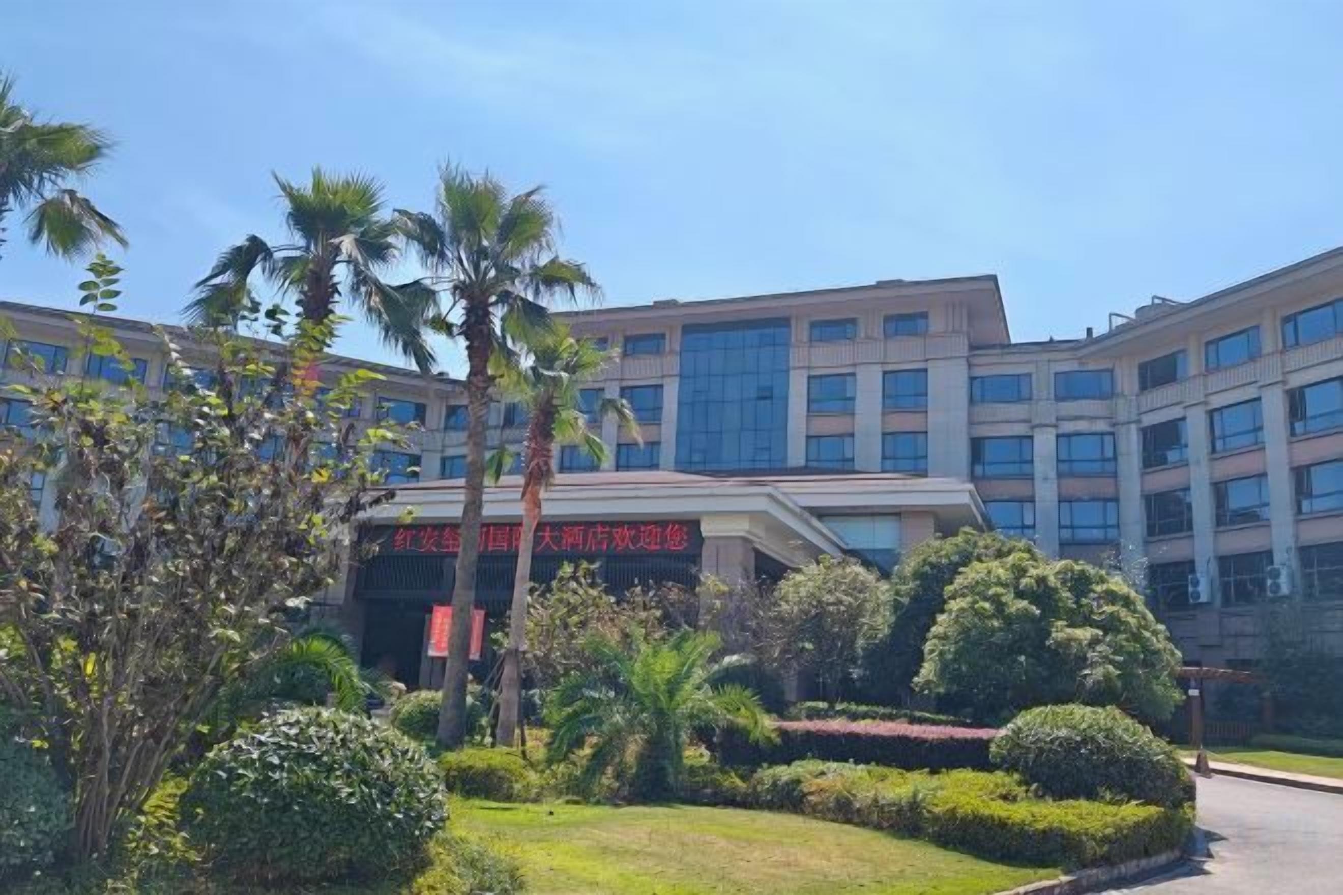 A multi-story building with a modern architectural design, surrounded by well-maintained landscaping including palm trees and shrubs.