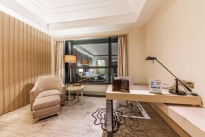 Une chambre d’hôtel équipée d’un bureau, d’une chaise, d’une lampe et offrant une vue par la fenêtre.
