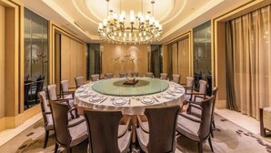 A round dining table with 12 chairs, a central glass-top table, and a large chandelier. - Xili International Hotel (Hong'an)
