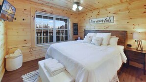 Une chambre confortable, aménagée dans un chalet en bois, avec un grand lit, une fenêtre et un panneau motivant accroché au mur.