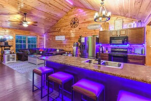 A log cabin interior with a kitchen, bar area, and living room. - Unique Stay | Incredible Lighting | Lux Hot Tub (Sevierville)
