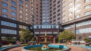 A high-rise building with a central courtyard featuring a fountain, surrounded by trees and parked vehicles. - Chongfu International Hotel (Shangcheng)