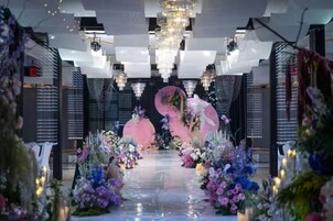 Un espacio interior con un escenario central, arreglos florales e iluminación moderna.