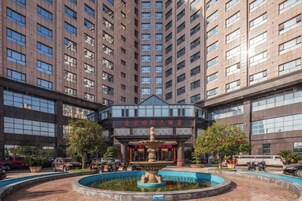Entrada de un hotel con una fuente, rodeada de edificios altos.