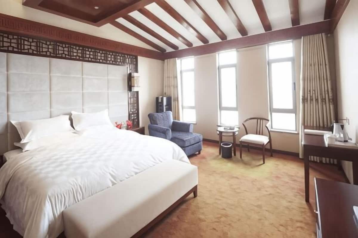 Una habitación de hotel con una cama grande, un escritorio, una silla, una mesita y un televisor.
