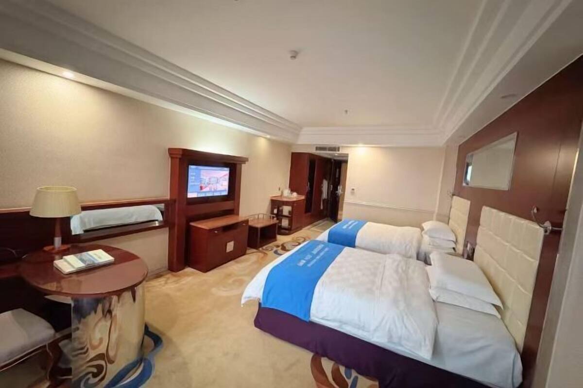 Habitación de hotel con cama, televisor, escritorio y una silla.