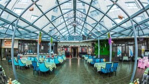 A spacious indoor restaurant with a high glass ceiling and green-striped tables and chairs. - Chongfu International Hotel (Shangcheng)