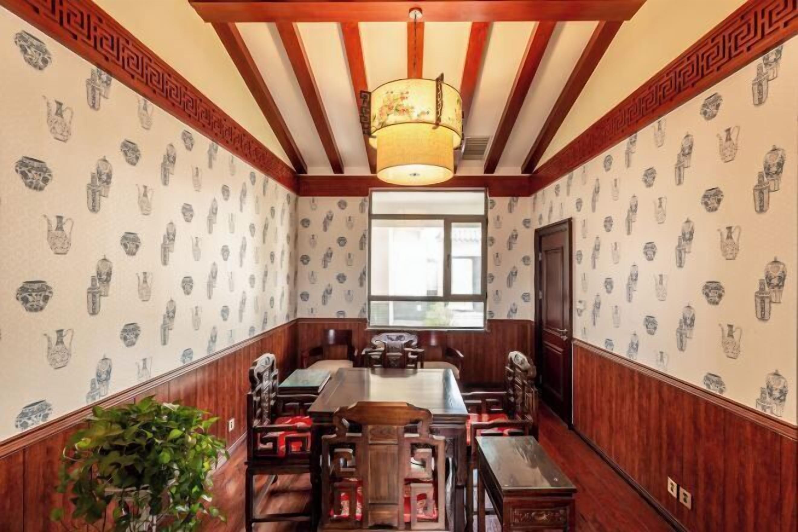 A traditional room with wooden paneling, a large dining table, and patterned wallpaper.