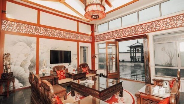 A traditional room with a wooden ceiling, a large window, and a view of a water body. - Chongfu International Hotel (Shangcheng)
