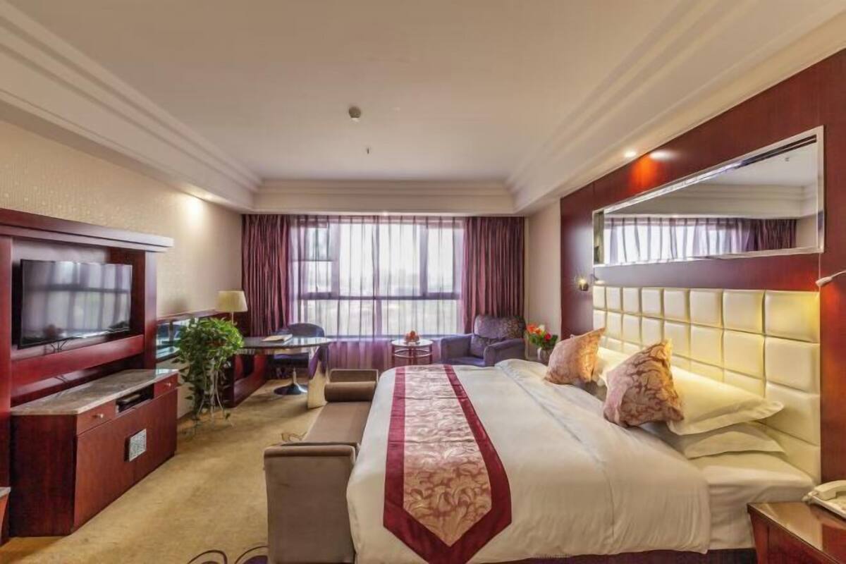 Una habitación de hotel con una cama grande, televisión, escritorio y una silla.