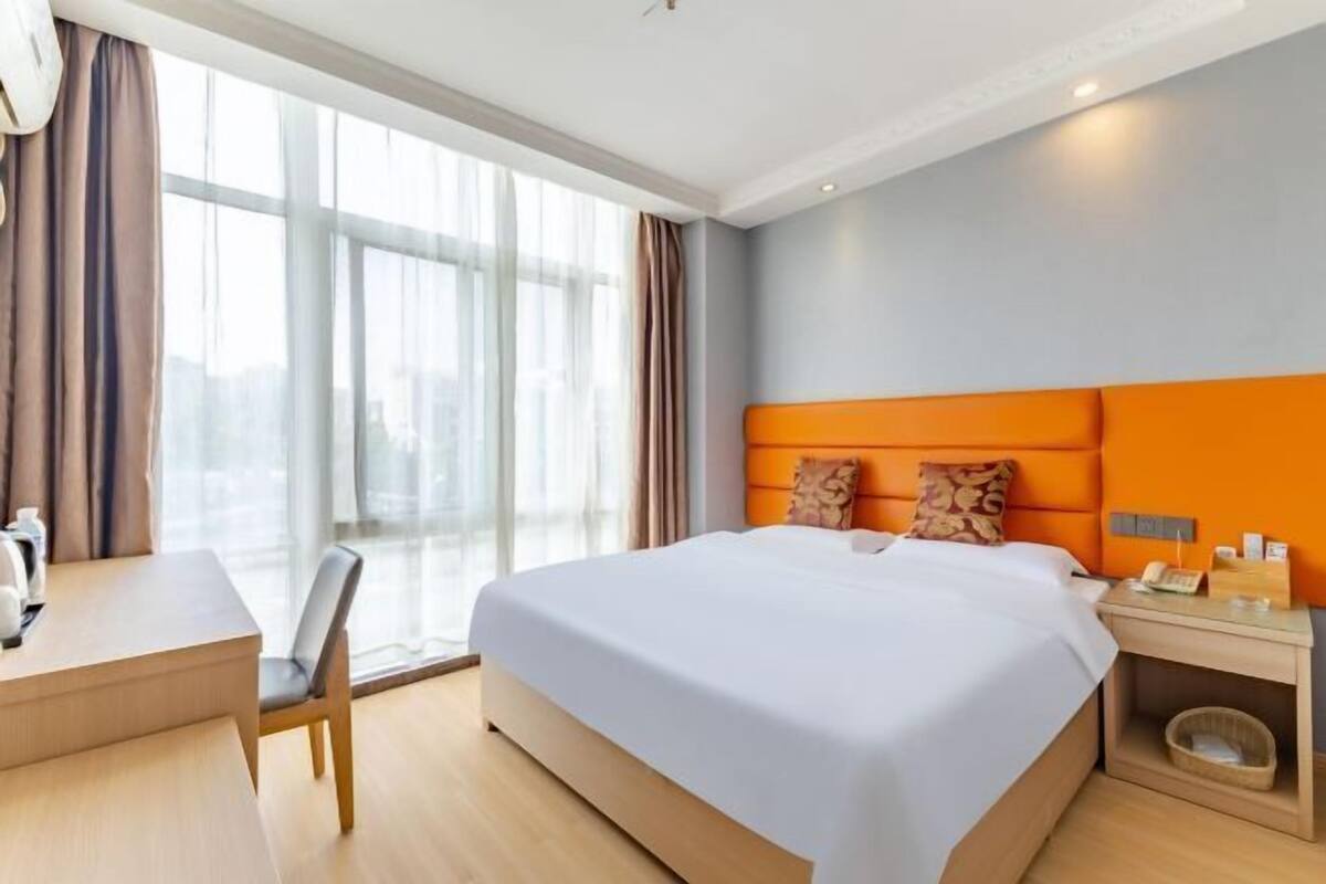 A hotel room with a large bed, a desk, and a chair.