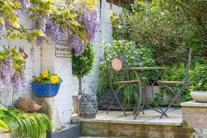 A garden with a table, chairs, and a sign on a wall.