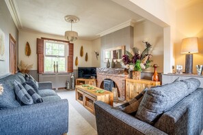 A living room with a fireplace, sofa, TV, and wooden table.