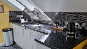 Une cuisine avec un dosseret à motifs noir et blanc, des appareils en acier inoxydable et un plan de travail noir.