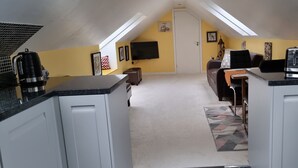 Une petite chambre mansardée comprenant un lit, un bureau et un coin cuisine.