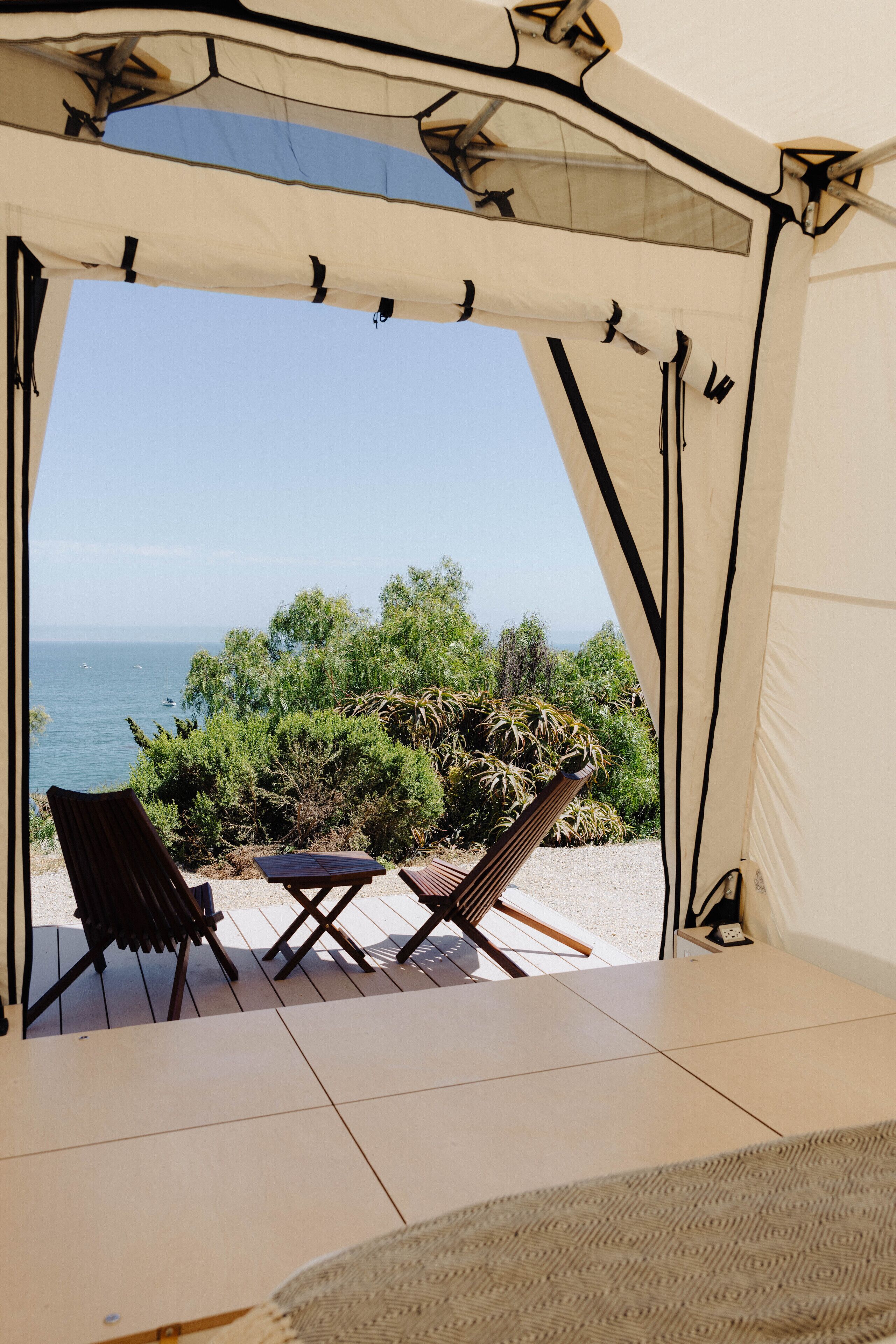 A tent with a view of the sea and greenery.