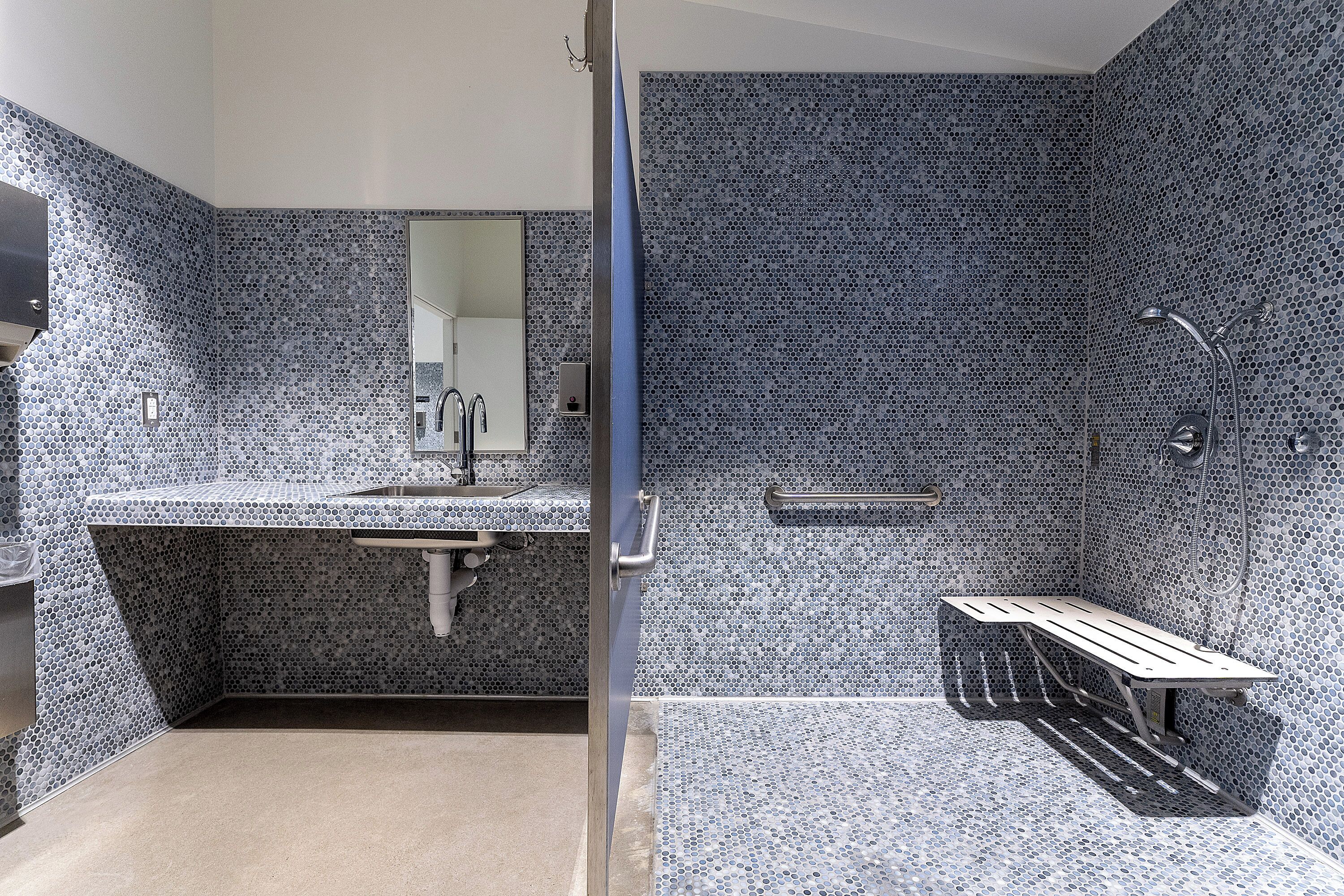 A modern bathroom with a sink, mirror, and shower area.