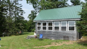 A small, single-story building with a green roof and multiple windows.