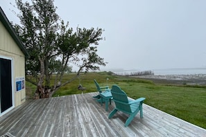 A wooden deck with turquoise Adirondack chairs and a sign for ice cream.