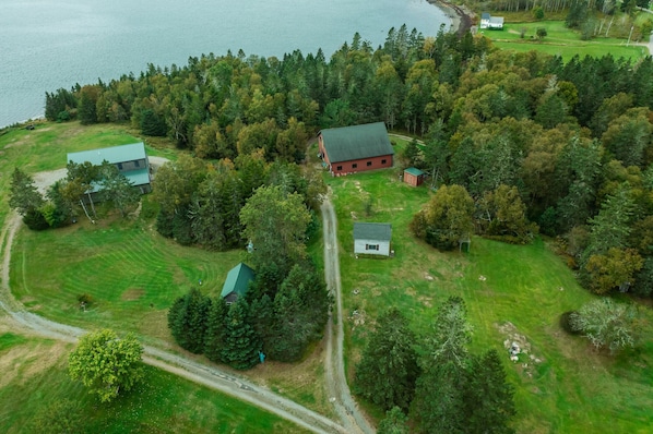 An aerial view of a rural property with multiple buildings, a golf course, and a lake.