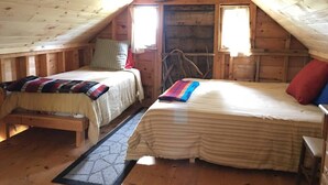 Una camera da letto mansardata accogliente, con due letti, pareti in legno e un soffitto spiovente.