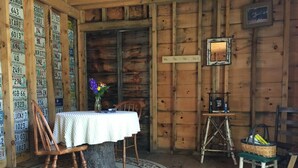 Un'accogliente interni in legno con un tavolo rotondo e sedie, un vaso con fiori e un quadro appeso al muro.