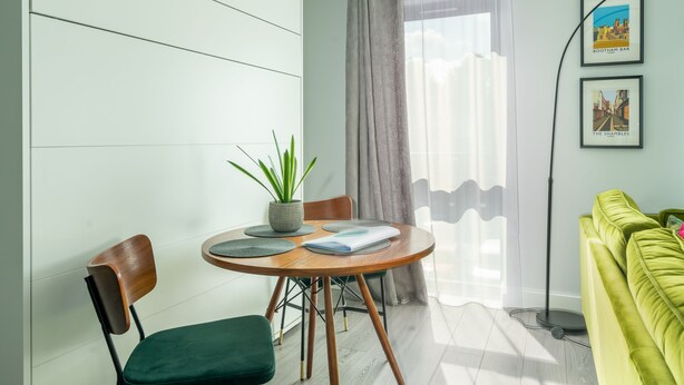 A modern living room with a round wooden table, two chairs, a green sofa, a potted plant, and framed pictures on the wall. - Bootham Row  11 -  a couples retreat that sleeps 3 guests  in 1 bedroom (York)