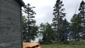 A wooden cabin with a wooden deck and steps leading to a door.