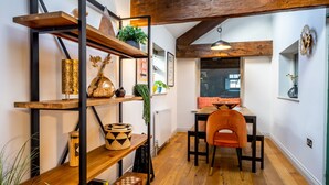 Un comedor con muebles de madera, estanterías con adornos y vigas de madera a la vista.