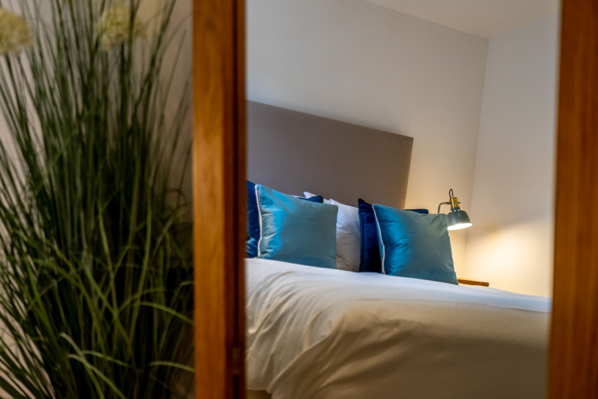 A bedroom with a bed, pillows, and a bedside lamp.