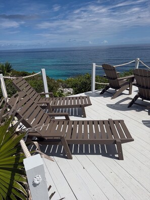 A deck with wooden lounge chairs facing a body of water. - Eleuthera Villa - The Surfer's Beach Destination! (Gregory Town)