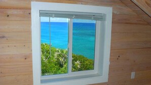 Una stanza con vista su una spiaggia tropicale e sull'oceano.
