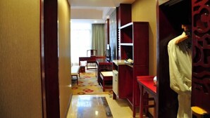 Habitación de hotel con escritorio, silla, armario y un maniquí.