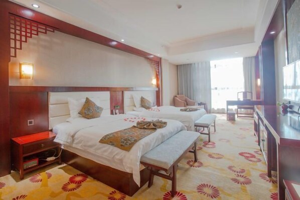 A hotel room with two beds, a bench, a desk, and a view of the city.