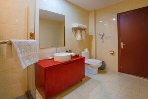 A bathroom with a red vanity, a white sink, a toilet, a mirror, and a towel rack.