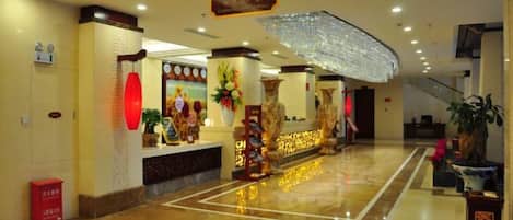 Un vestíbulo de hotel con una mesa de recepción, una escalera y un gran paraguas decorativo.