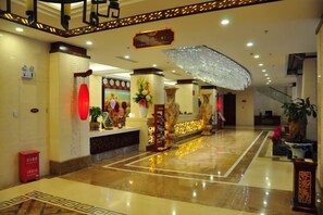 A hotel lobby with a reception desk, a staircase, and a large decorative umbrella.